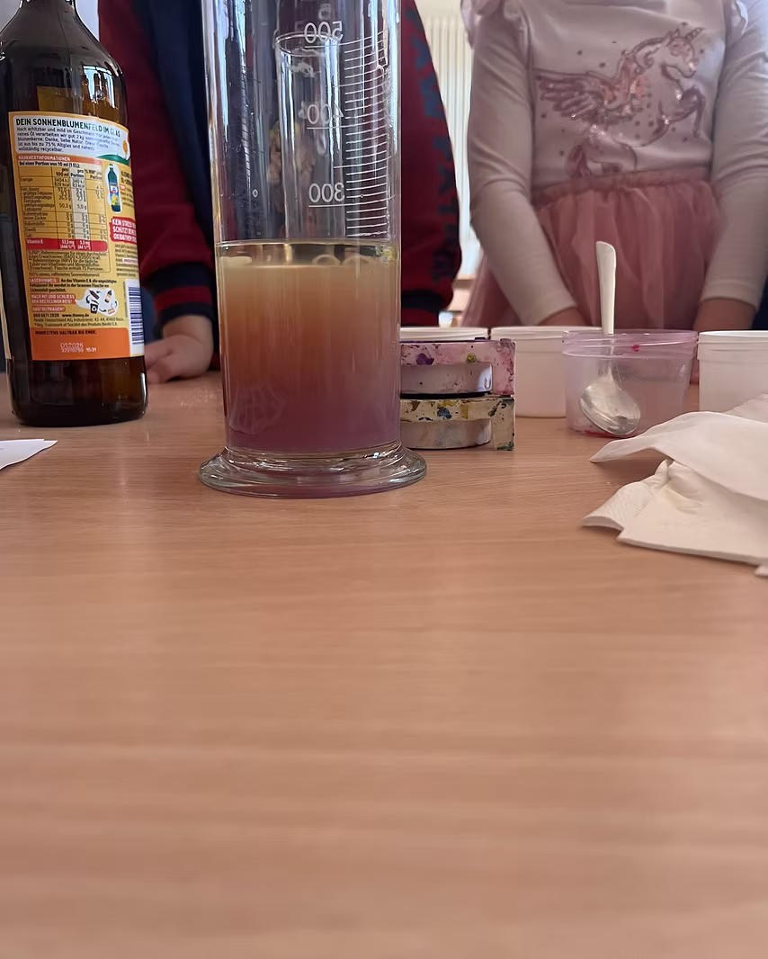 Kinder beobachten ein Experiment mit einem Messzylinder